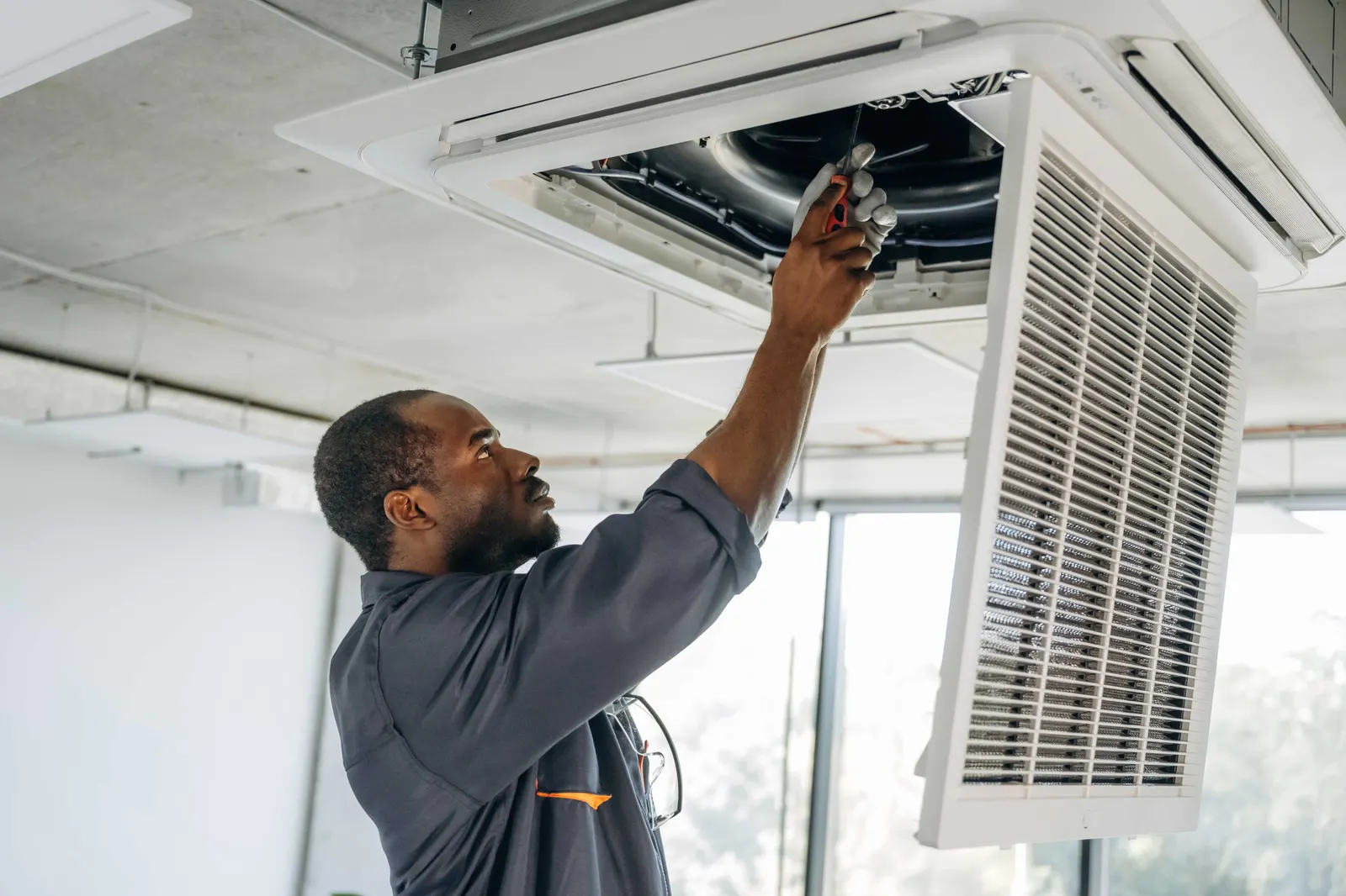 Technicien EMICA installant une unité de ventilation au plafond